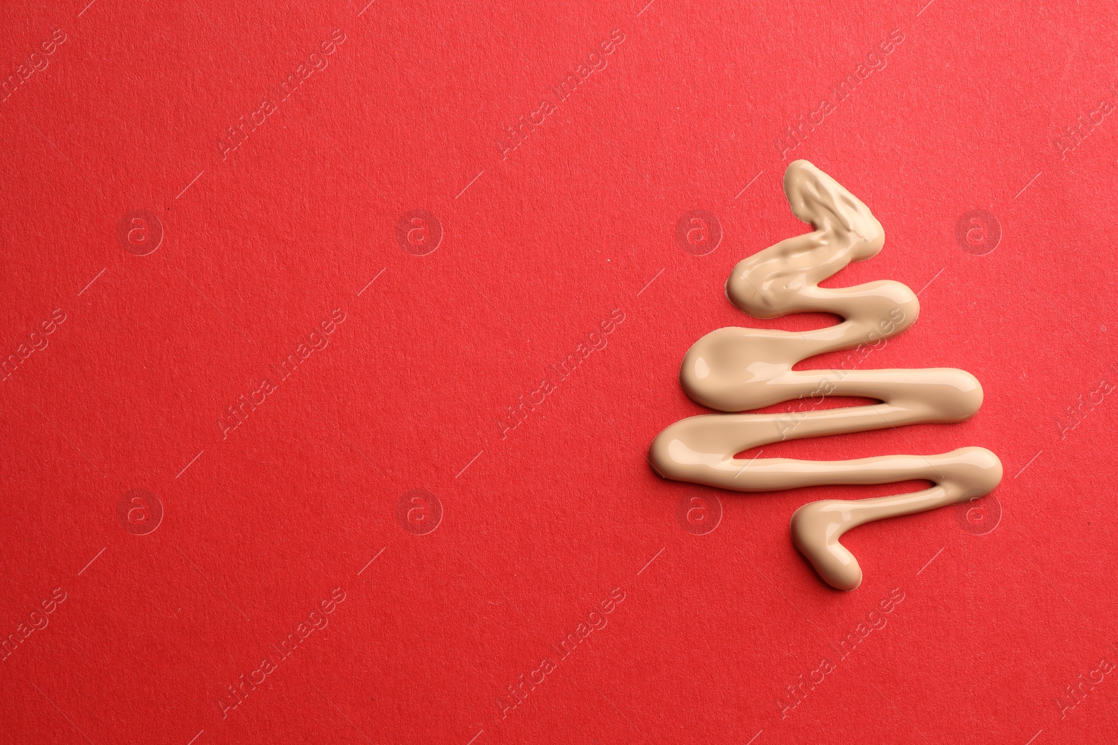 Photo of Christmas tree made of skin foundation on red background, top view. Space for text