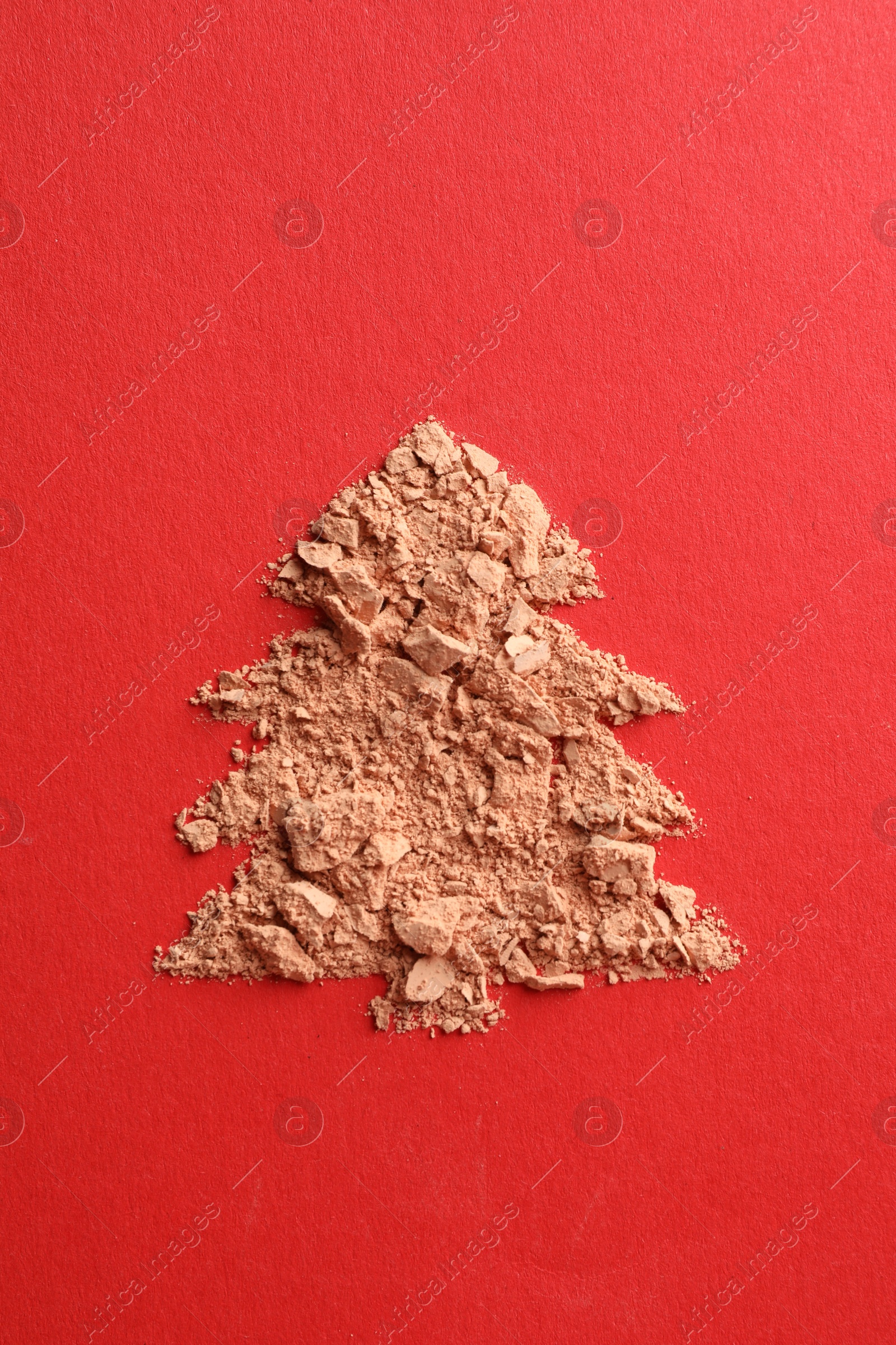 Photo of Christmas tree made of face powder on red background, top view