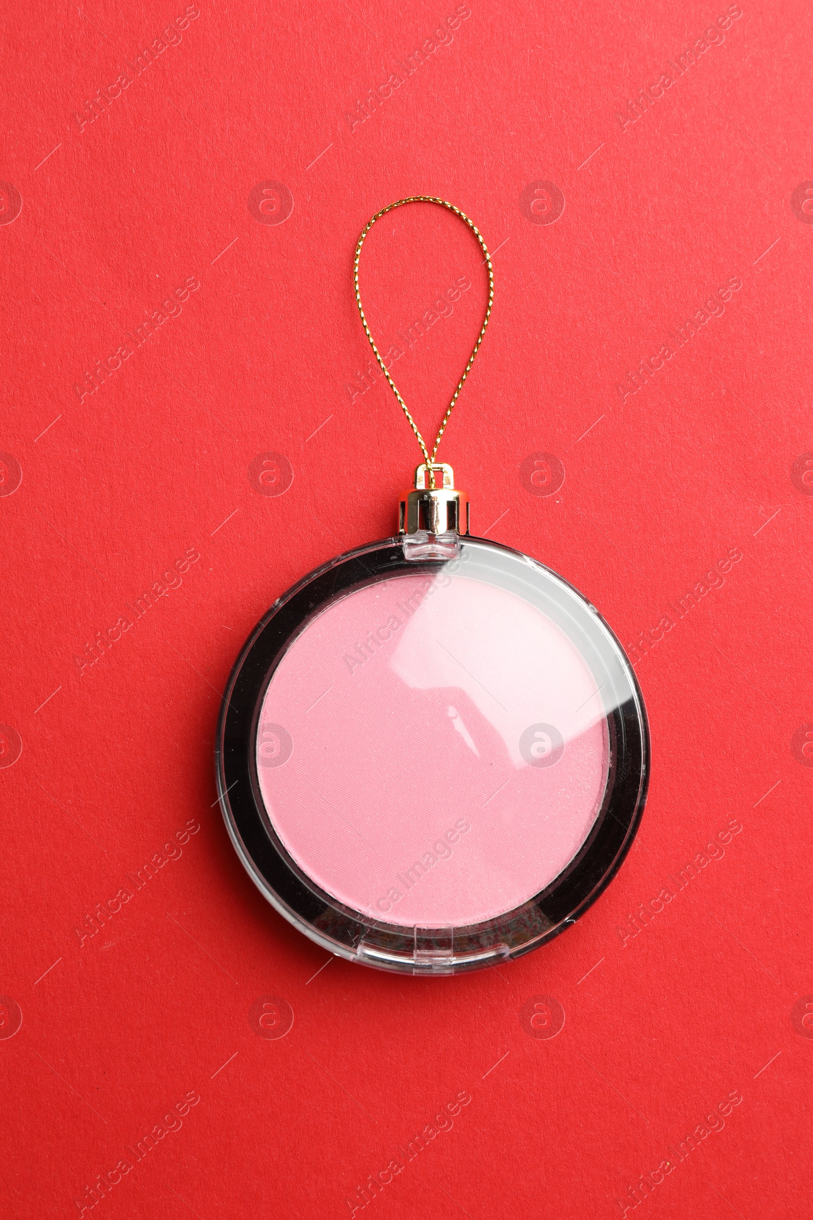 Photo of Blusher in shape of Christmas ball on red background, top view