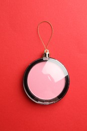 Photo of Blusher in shape of Christmas ball on red background, top view