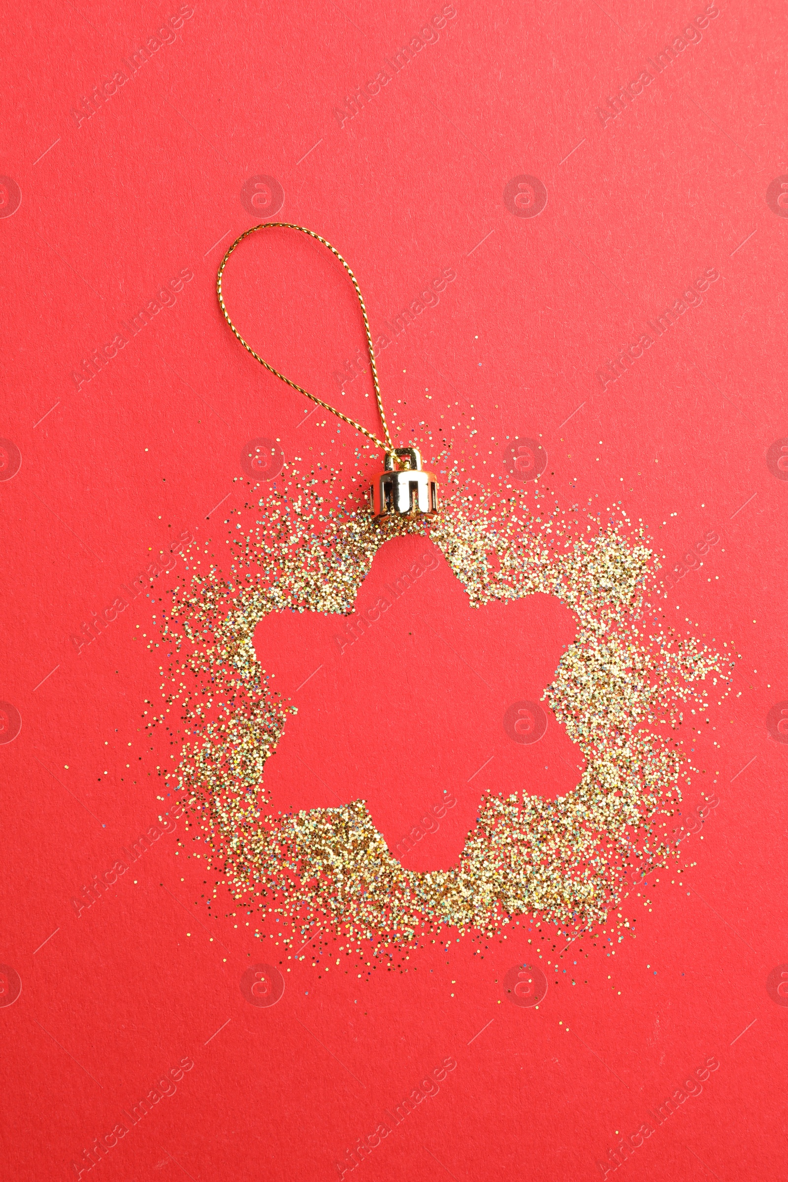 Photo of Christmas ornament made of golden glitter on red background, top view