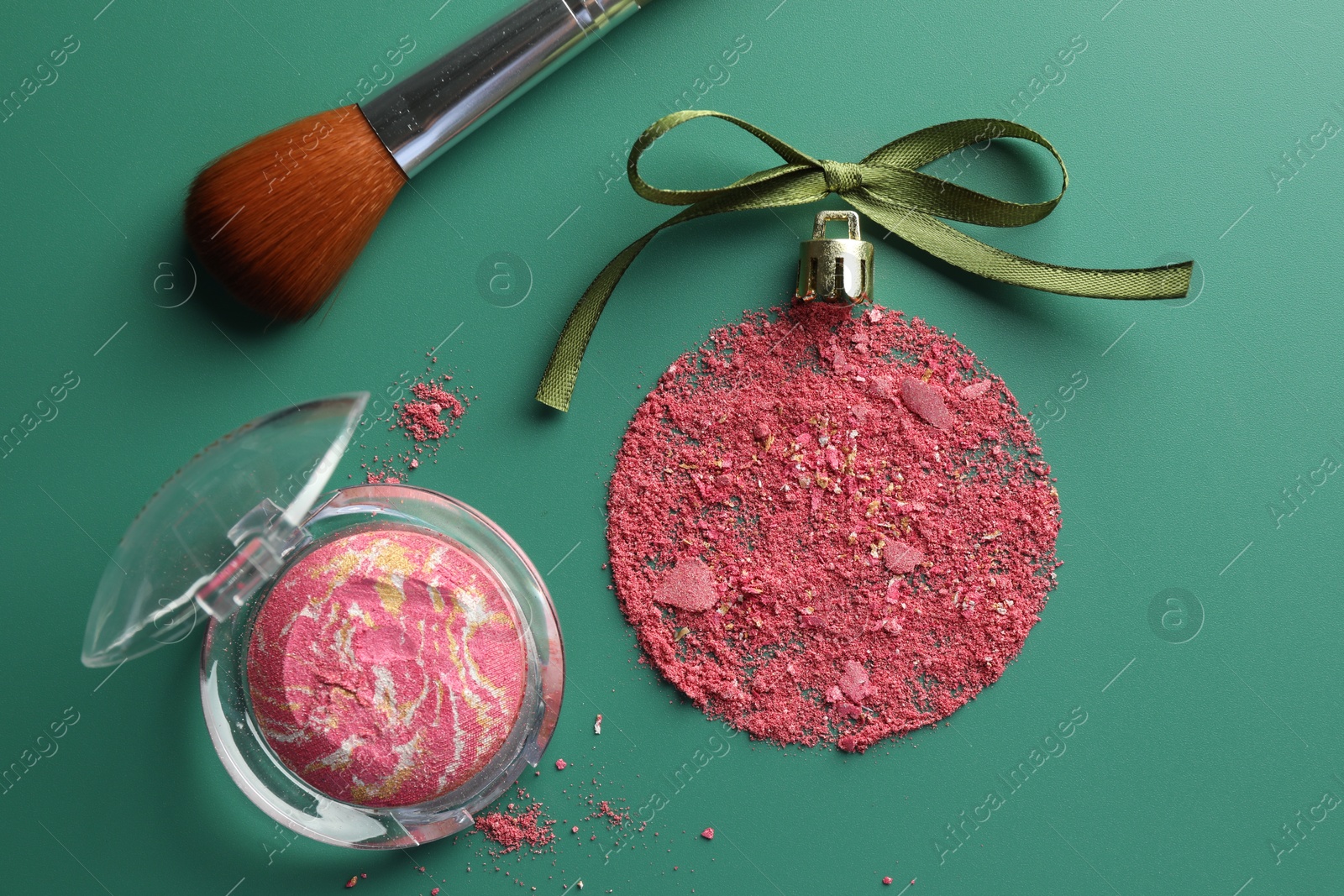 Photo of Christmas ball made of blush, bow and brush on green background, flat lay