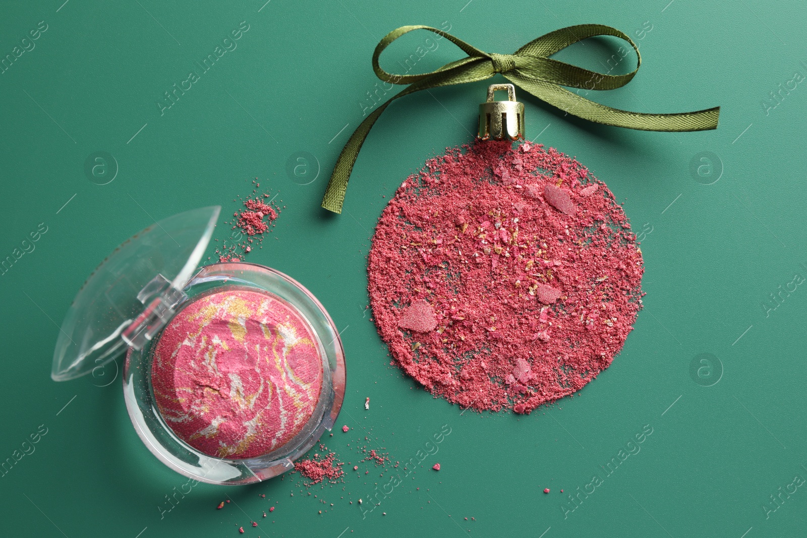 Photo of Christmas ball made of blush and bow on green background, top view