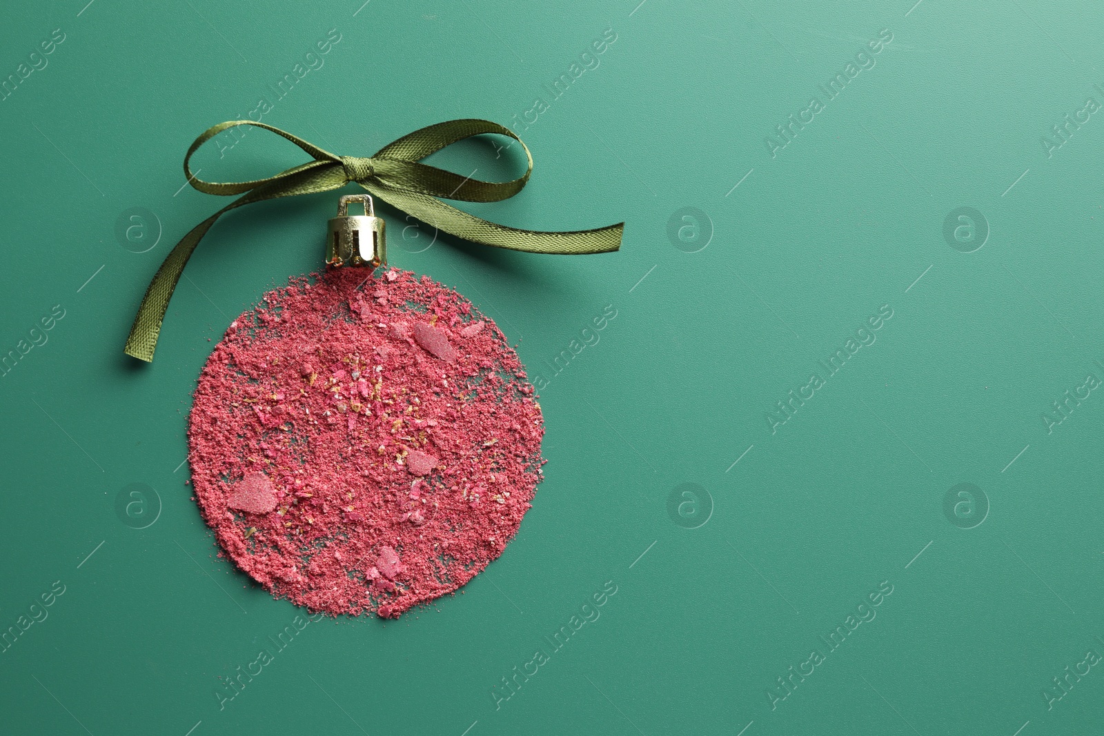 Photo of Christmas ball made of blush and bow on green background, top view. Space for text