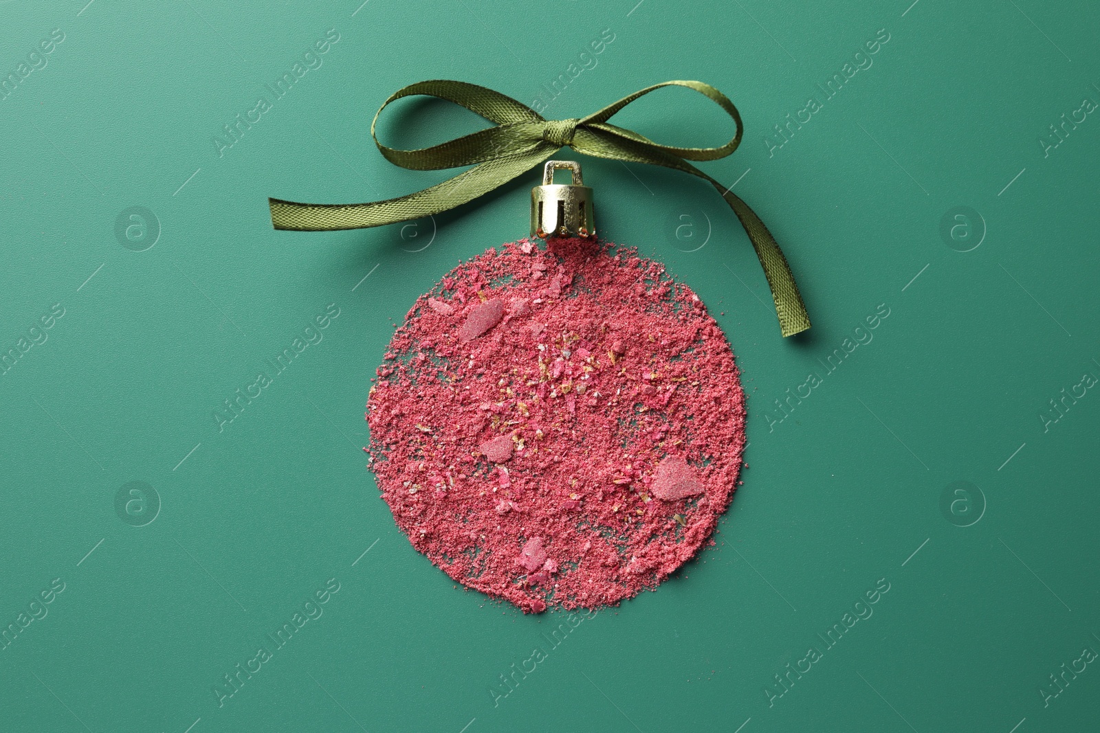 Photo of Christmas ball made of blush and bow on green background, top view