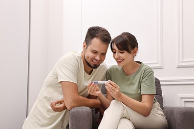 Photo of Happy young couple with pregnancy test at home