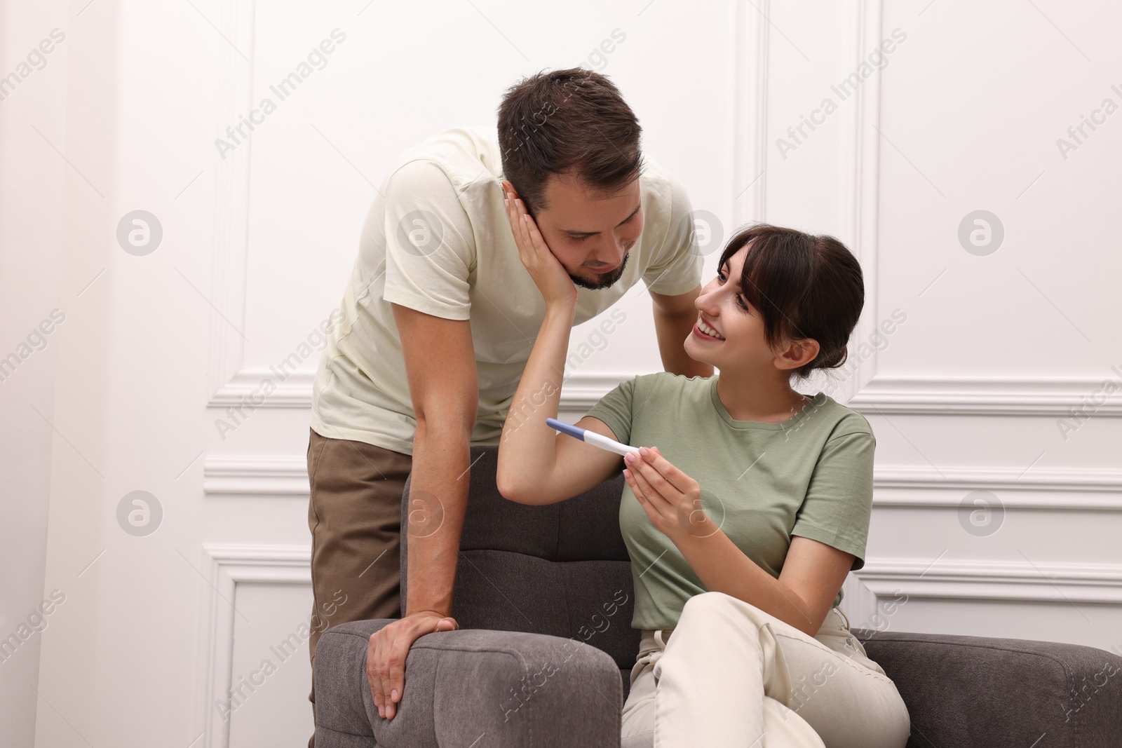 Photo of Happy young couple with pregnancy test at home