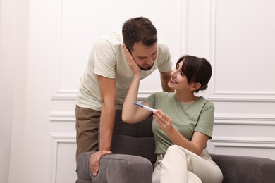 Happy young couple with pregnancy test at home