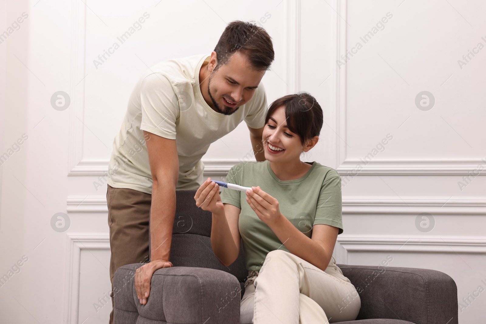 Photo of Happy young couple with pregnancy test at home