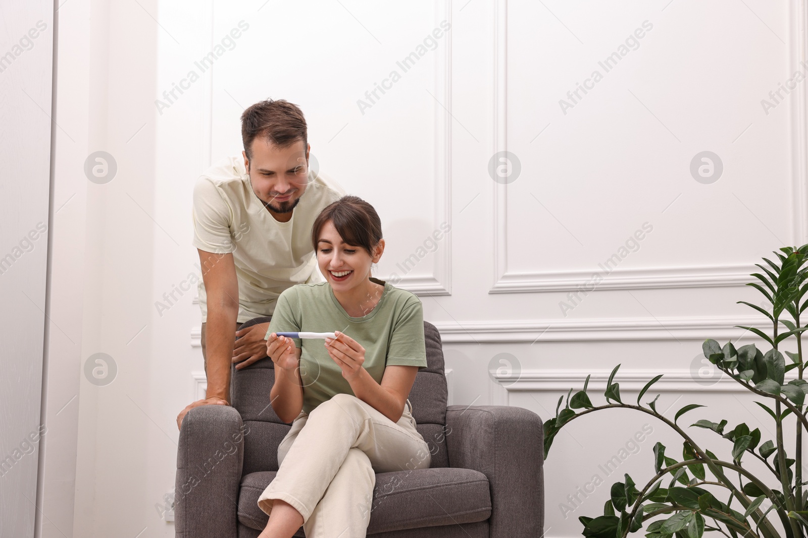 Photo of Happy young couple with pregnancy test at home