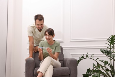 Happy young couple with pregnancy test at home