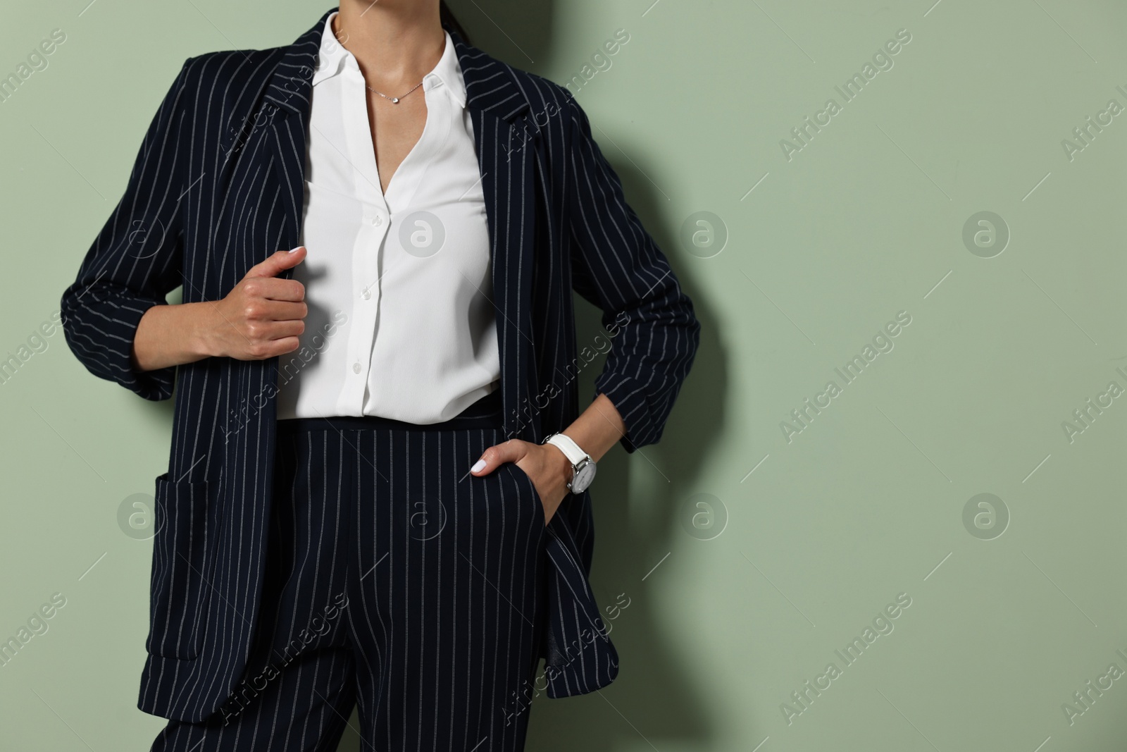 Photo of Woman in black striped suit on green background, closeup. Space for text