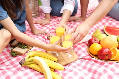 Photo of Family having picnic on checkered blanket outdoors, closeup