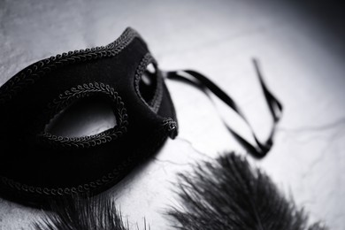 Photo of Beautiful carnival mask and feathers on grey table, closeup