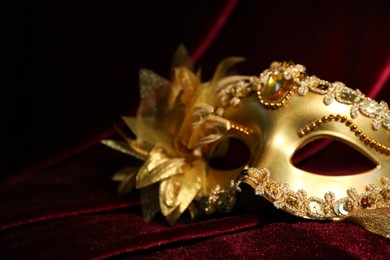 Beautiful golden carnival mask on red silk fabric, closeup