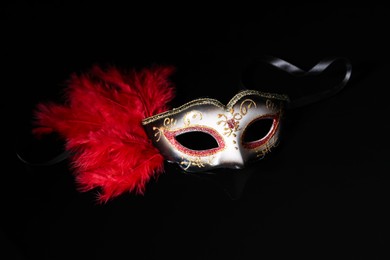 Photo of Beautiful carnival mask in darkness, closeup view