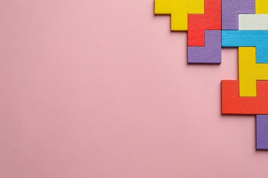 Photo of Colorful wooden puzzle pieces on pink background, top view. Space for text