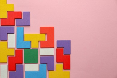 Photo of Colorful wooden puzzle pieces on pink background, top view. Space for text