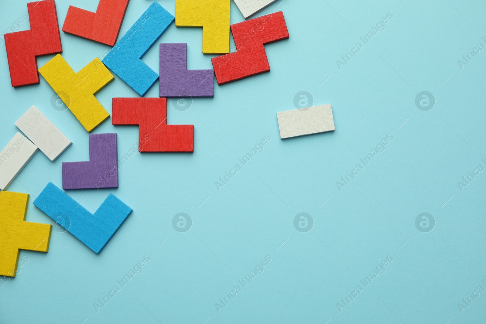 Photo of Colorful wooden puzzle pieces on light blue background, top view. Space for text