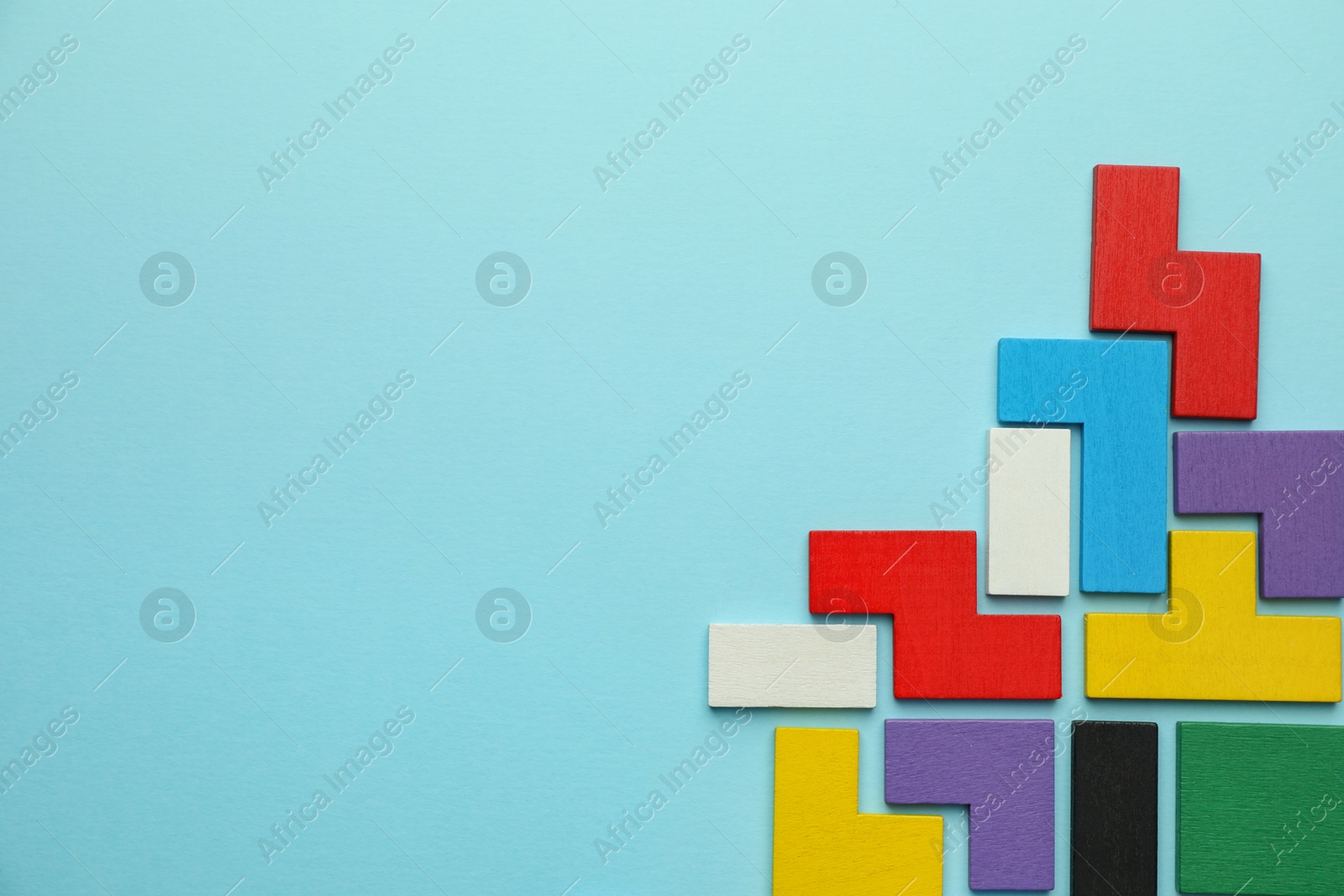 Photo of Colorful wooden puzzle pieces on light blue background, top view. Space for text