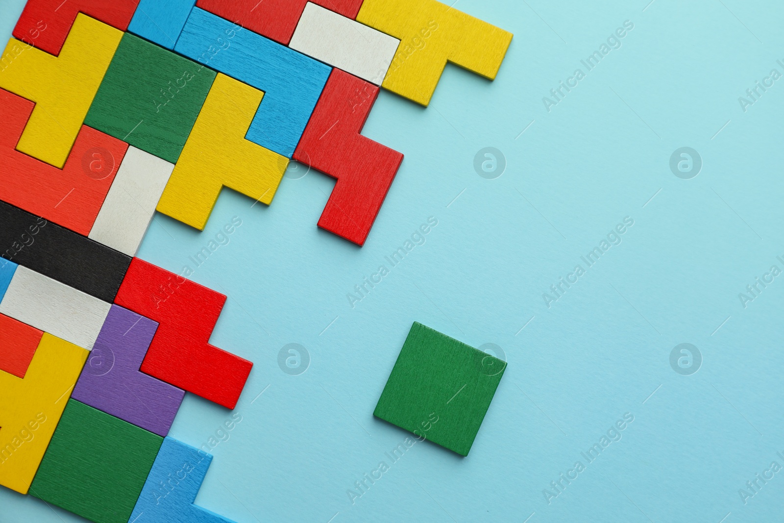 Photo of Colorful wooden puzzle pieces on light blue background, top view. Space for text