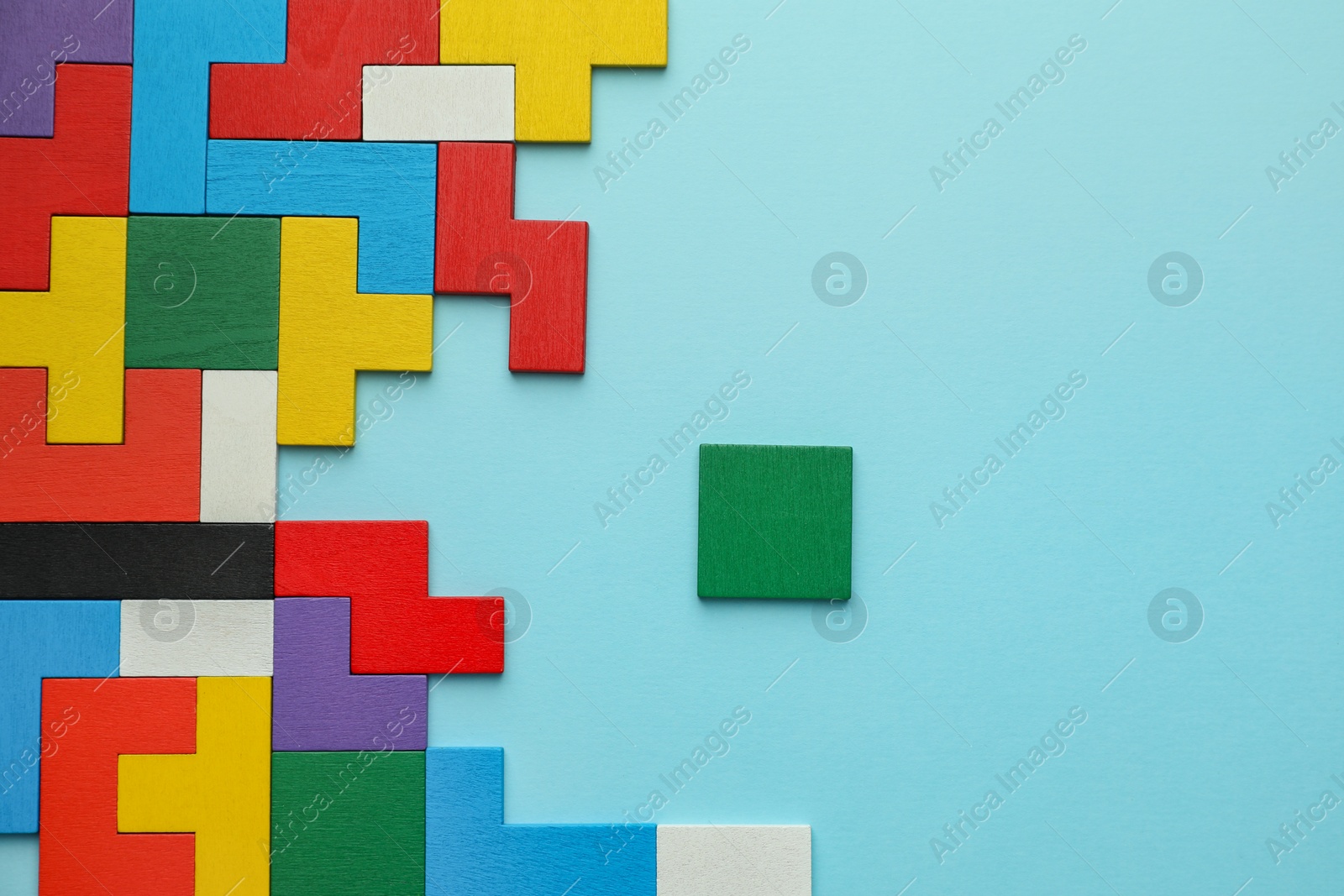 Photo of Colorful wooden puzzle pieces on light blue background, top view. Space for text