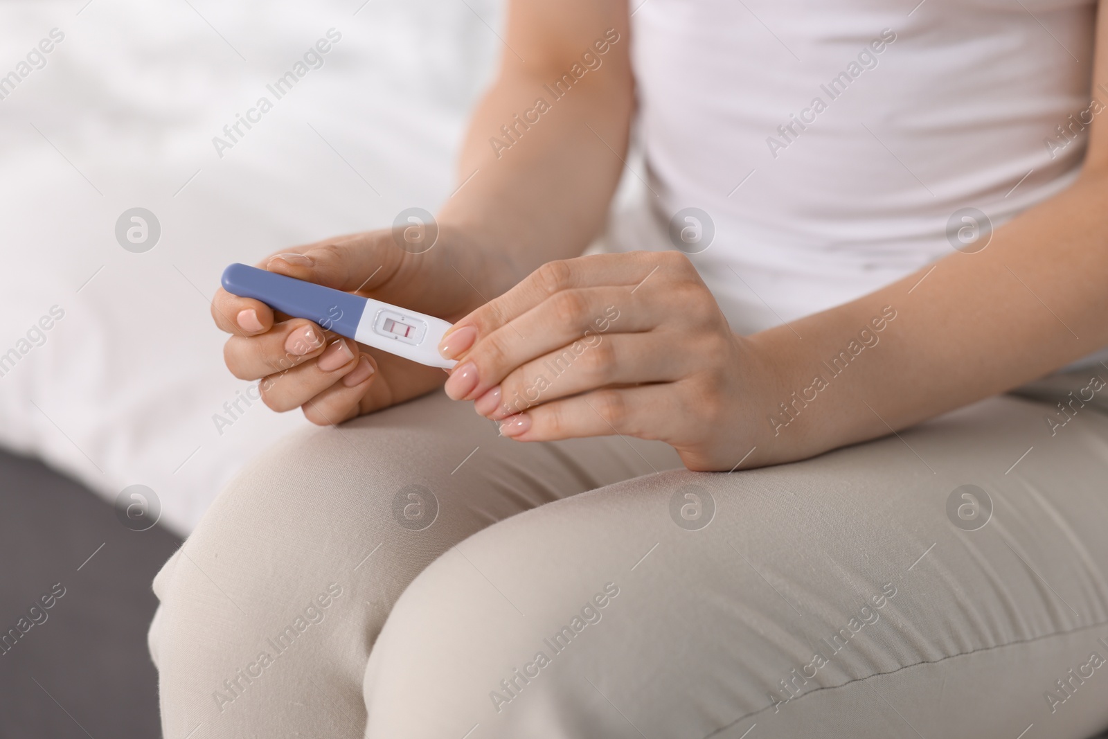 Photo of Woman holding pregnancy test in room, closeup