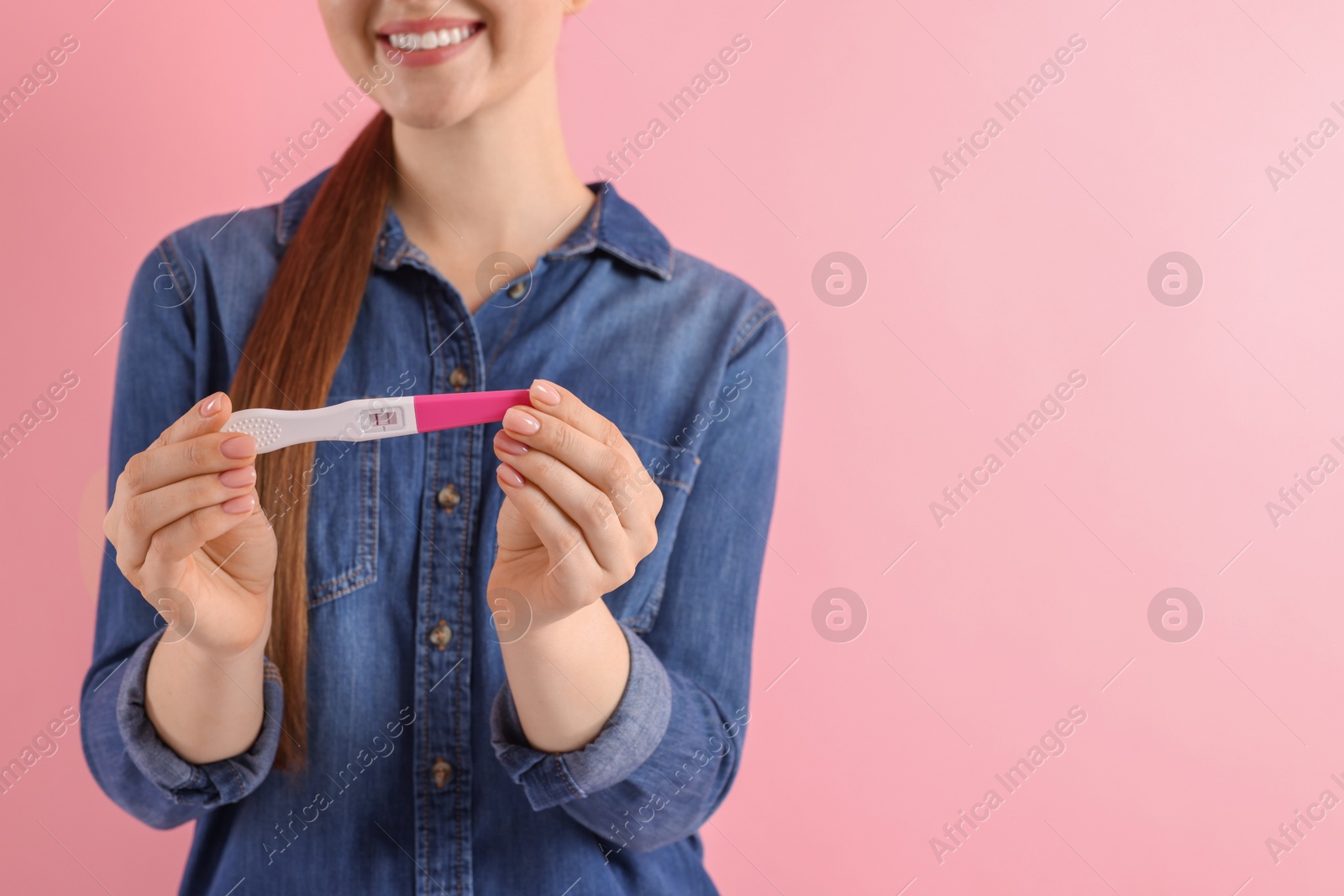 Photo of Woman holding pregnancy test on pink background, closeup. Space for text