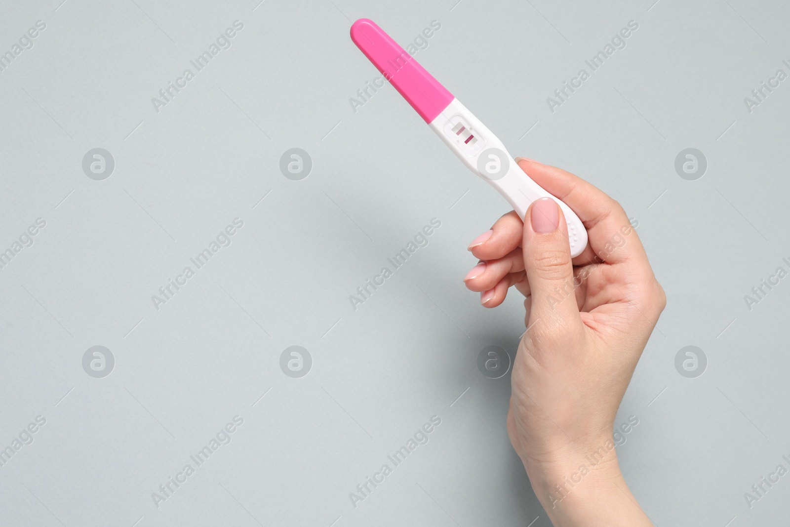 Photo of Woman with pregnancy test on light grey background, top view. Space for text