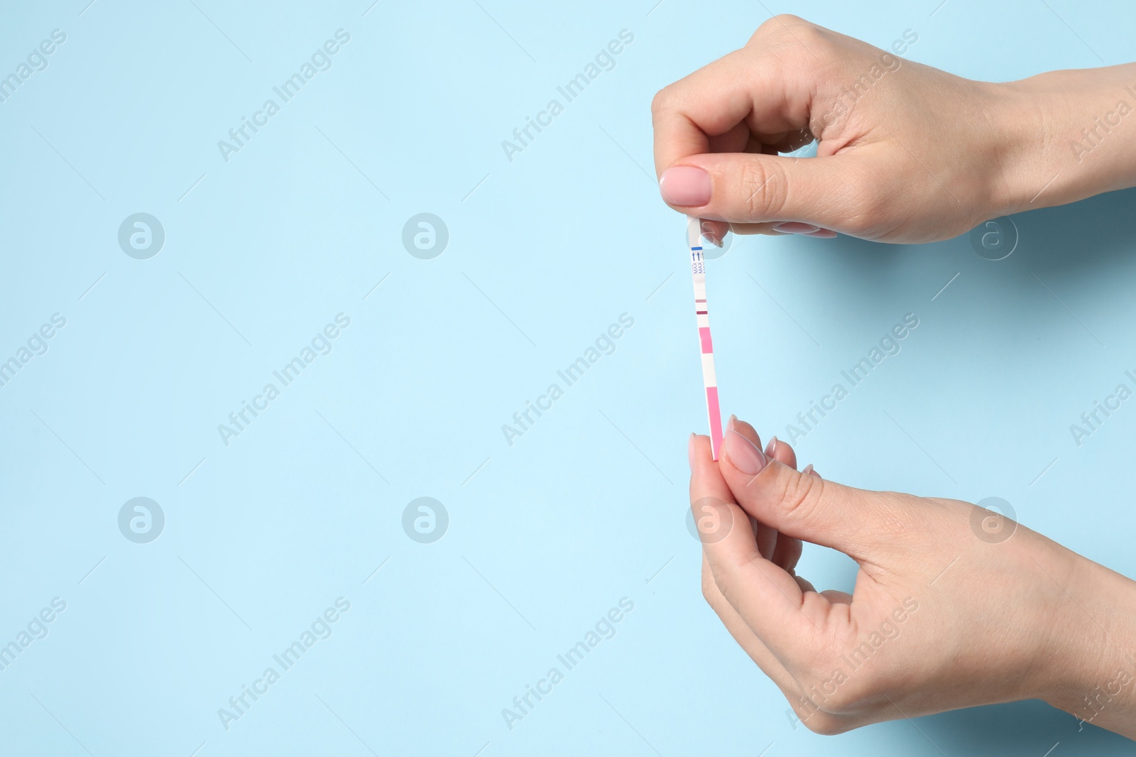 Photo of Woman with pregnancy test on light blue background, top view. Space for text