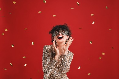 Photo of Happy young woman wearing carnival mask on red background with confetti