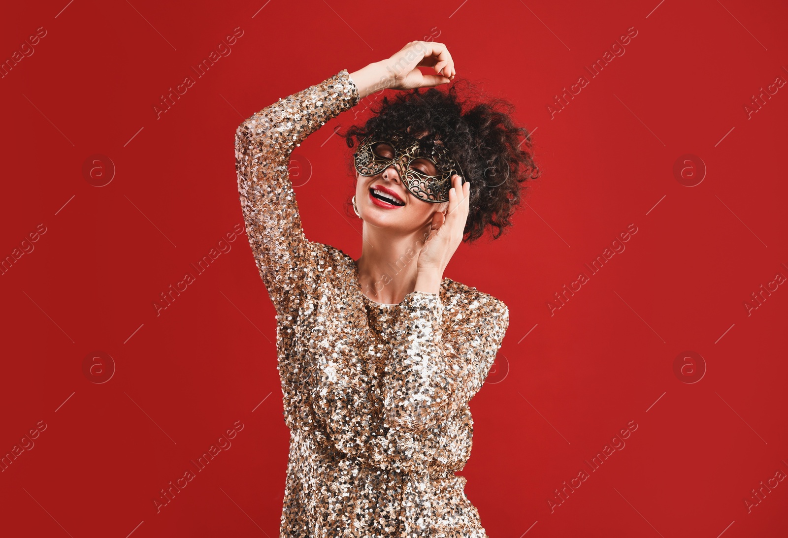 Photo of Happy young woman with carnival mask on red background