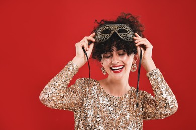 Photo of Happy young woman with carnival mask on red background