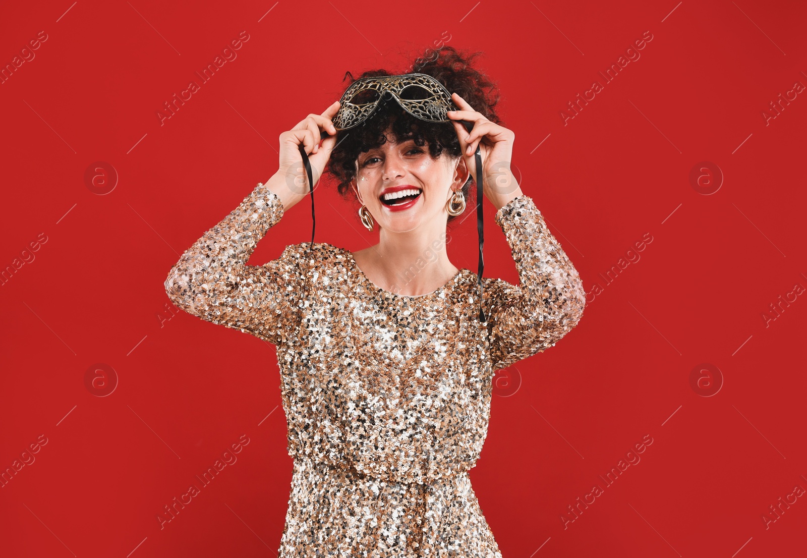 Photo of Happy young woman with carnival mask on red background