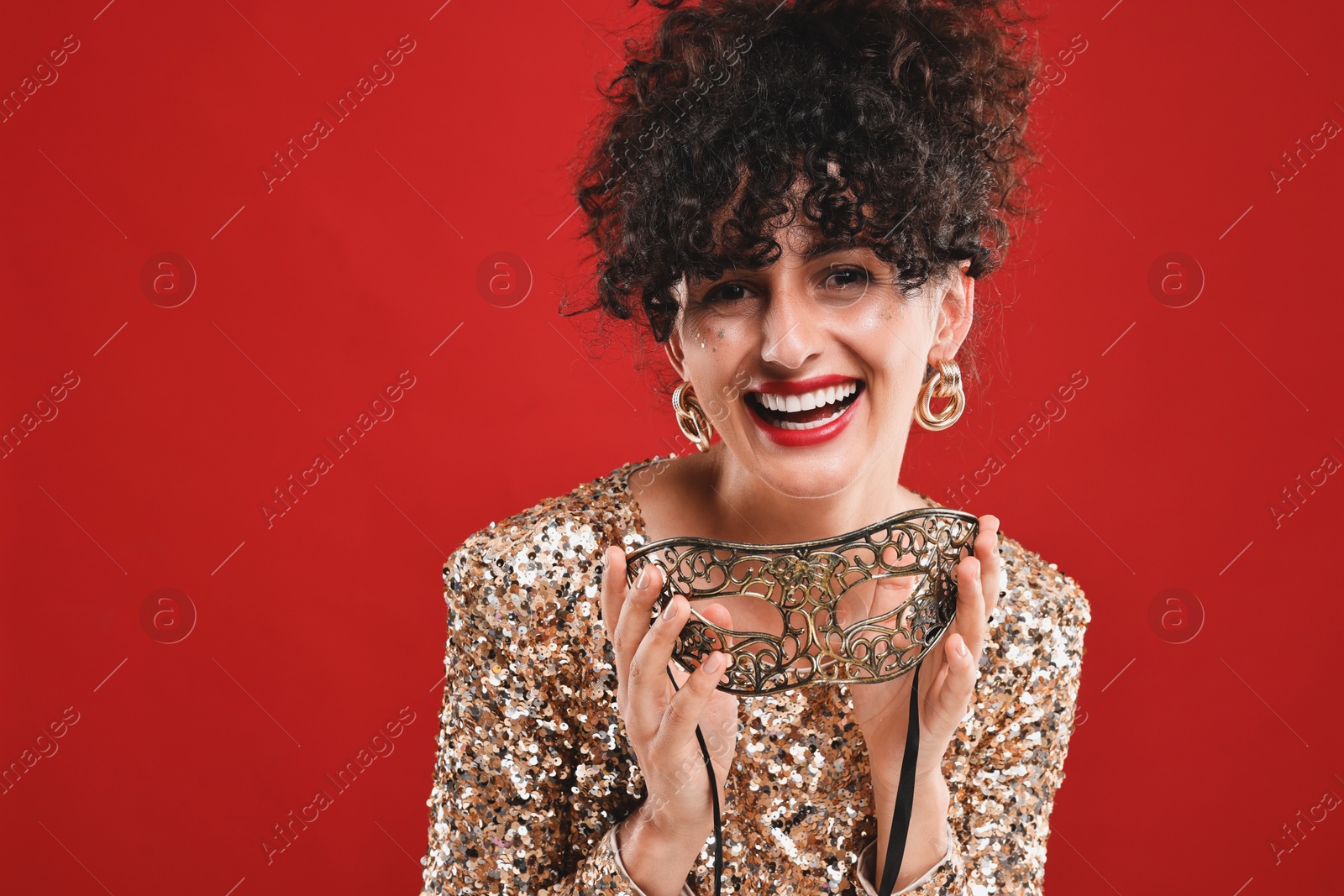 Photo of Happy young woman with carnival mask on red background