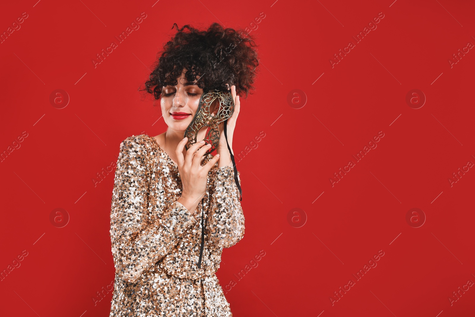 Photo of Beautiful young woman with carnival mask on red background, space for text