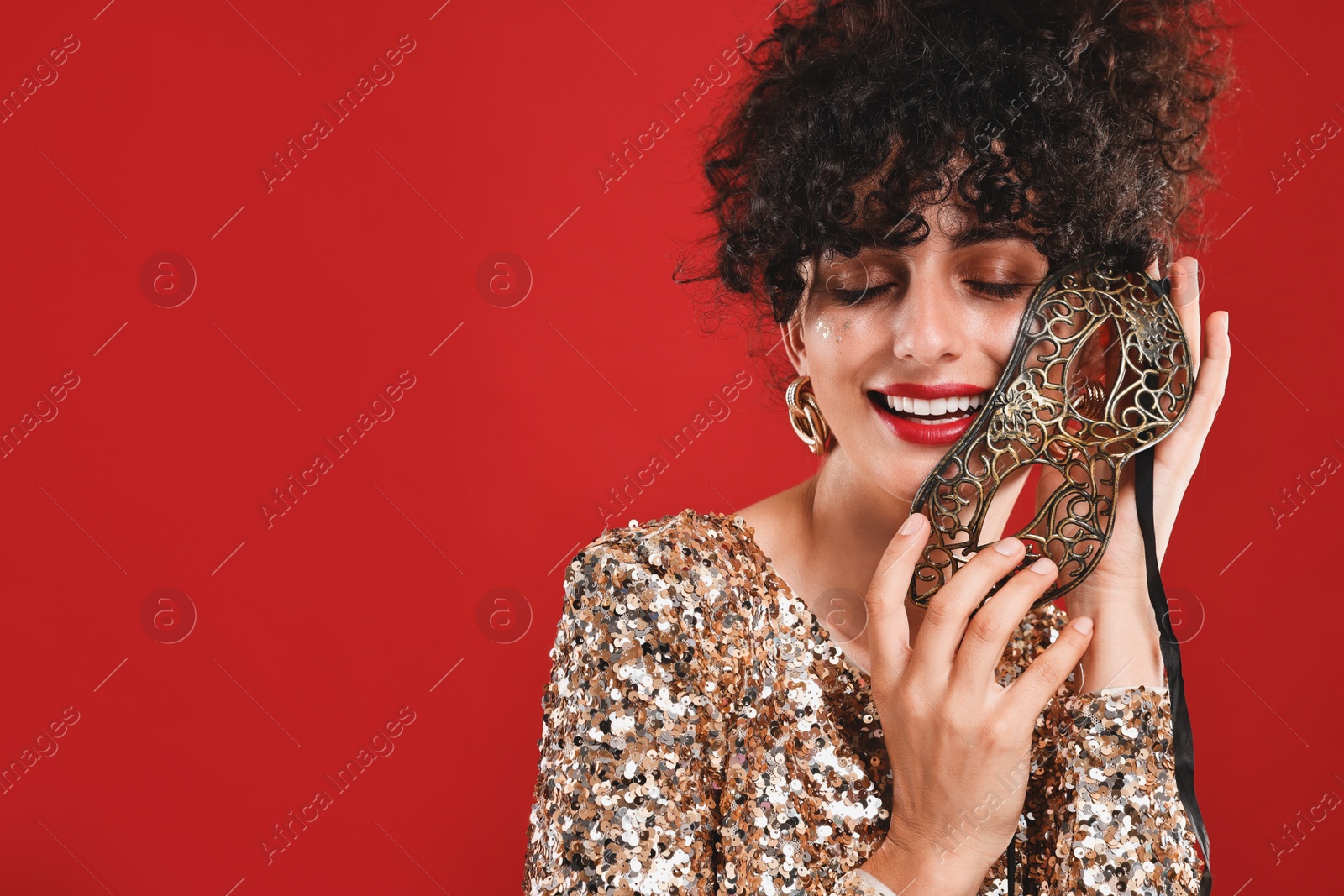 Photo of Smiling young woman with carnival mask on red background, space for text