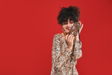 Smiling young woman with carnival mask on red background, space for text