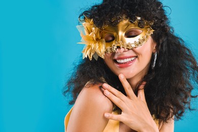 Photo of Happy young woman wearing carnival mask on light blue background