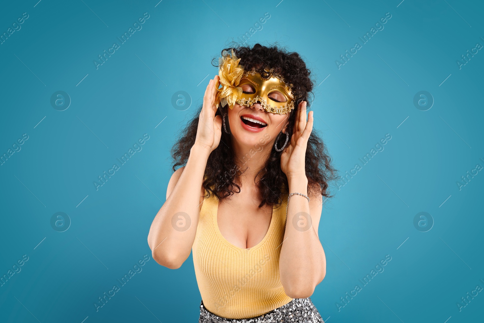 Photo of Happy young woman wearing carnival mask on light blue background