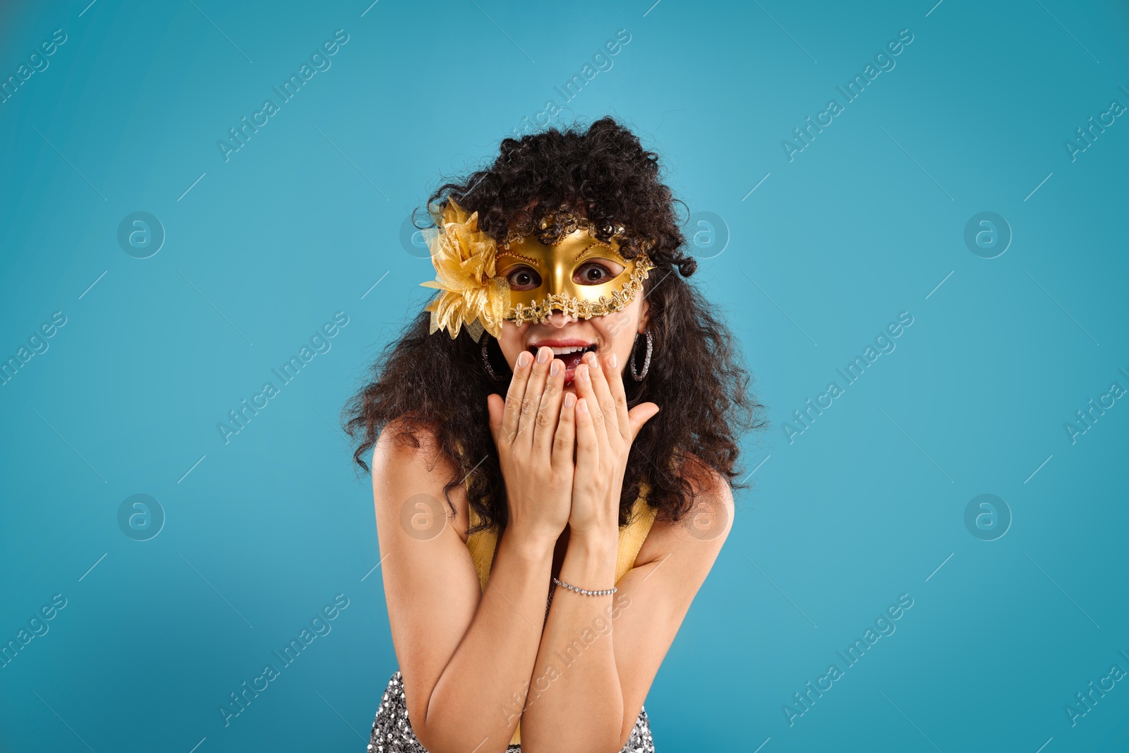 Photo of Emotional young woman wearing carnival mask on light blue background