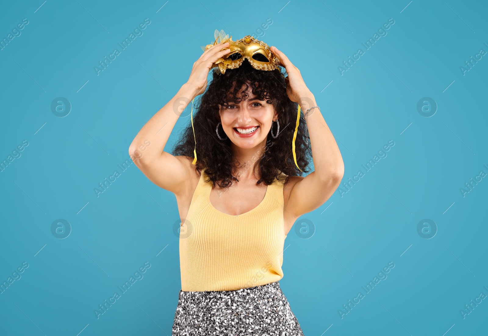 Photo of Happy young woman with carnival mask on light blue background