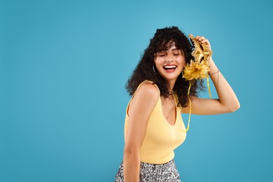 Happy young woman with carnival mask on light blue background, space for text