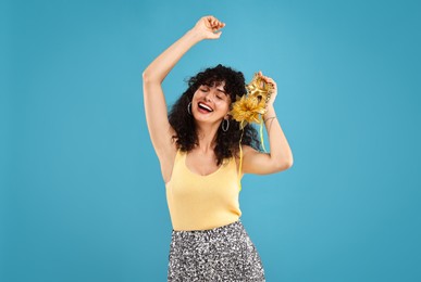 Photo of Happy young woman with carnival mask on light blue background