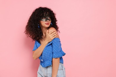 Beautiful young woman wearing carnival mask on pink background, space for text