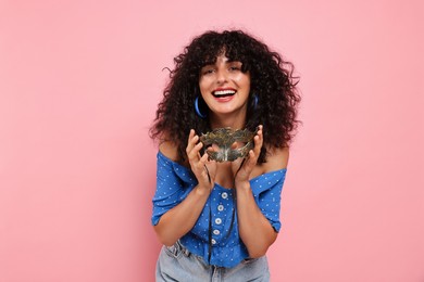 Smiling young woman with carnival mask on pink background