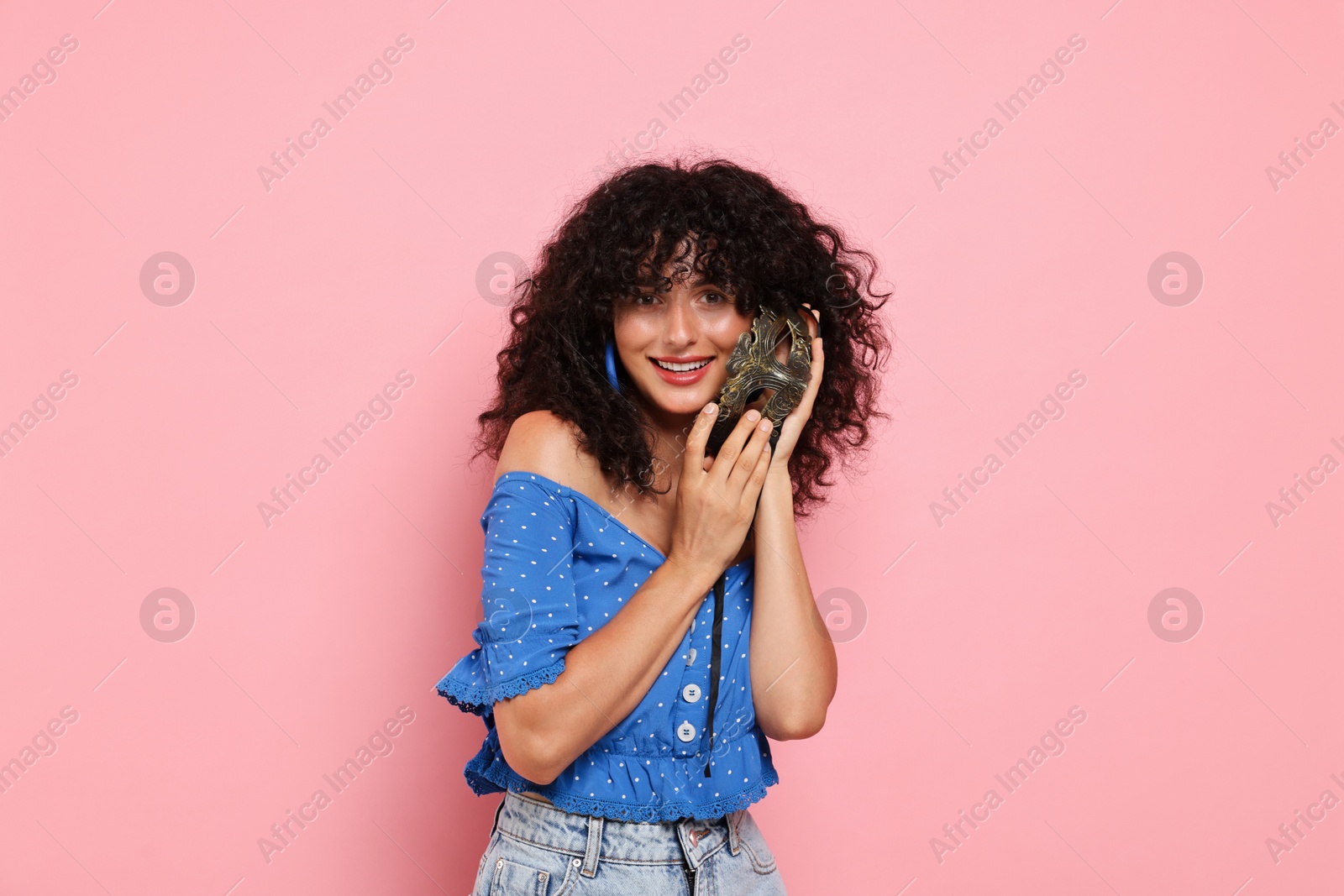 Photo of Smiling young woman with carnival mask on pink background