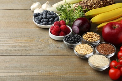 Photo of Different fresh products on wooden table, space for text. Source of prebiotics