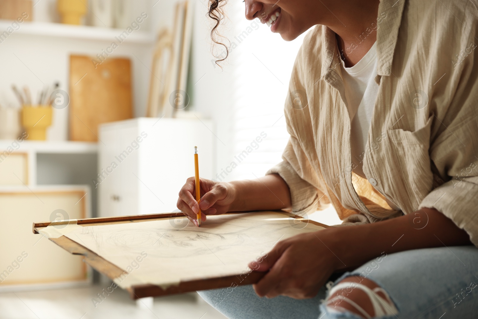 Photo of Smiling woman drawing portrait with pencil in studio, closeup