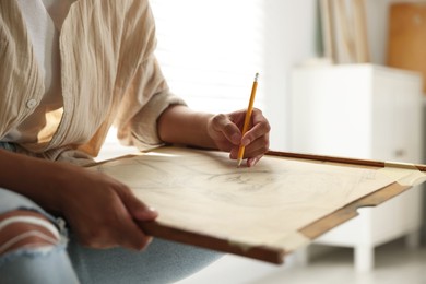 Woman drawing portrait with pencil in studio, closeup